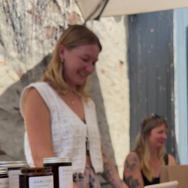 A maker smiling behind her candle stall at a market